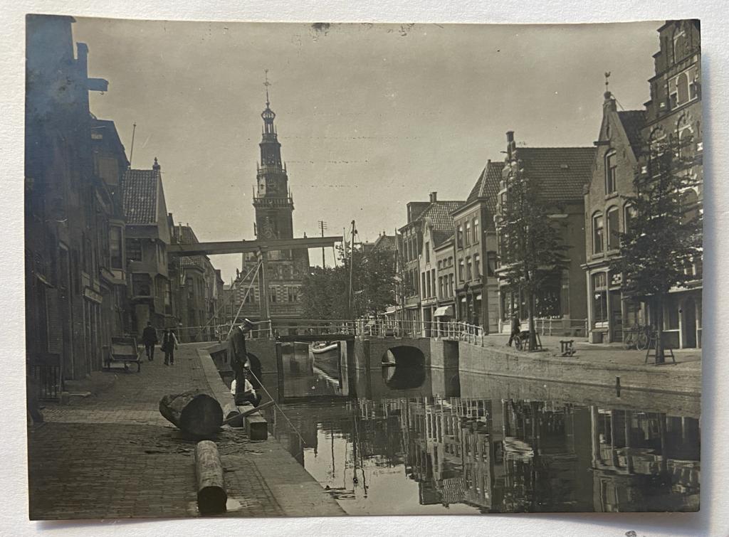 [2 antique photo's, 2 foto's, Alkmaar] Two original photo's with street and canal in Alkmaar. Old car driving, and fishing man in front of the church and suspension bridge (hangbrug). ed around 1800. (kopie)