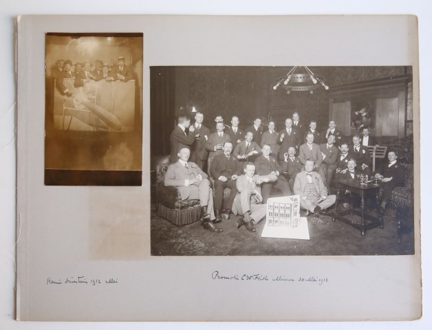 Foto van groep personen bij promotie van C.W.Feith op Minerva. Op de voorgrond model van een huis in suikergoed (zijn studentenhuis?) 1913