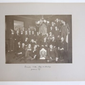 Groepsfoto van promotiepartij van V. Six, bij Pijl in Leiden. Op de voorgrond model in suikergoed van een kerkachtig huis. Verso: groepsfoto Collation 9-2-1914 1914